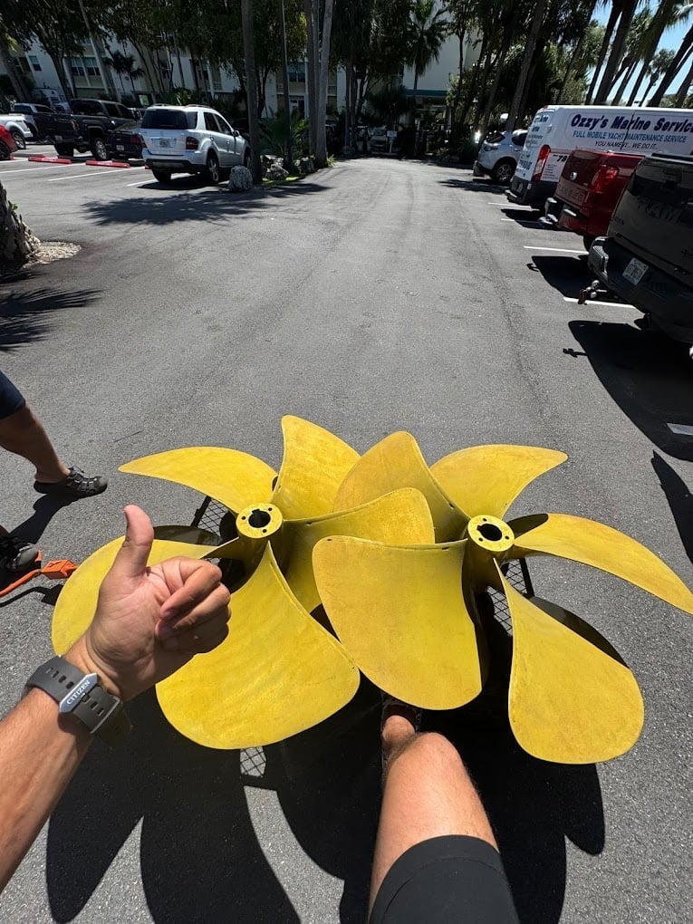 Person holding yellow toy drones with propellers in a parking lot with vehicles and palm trees