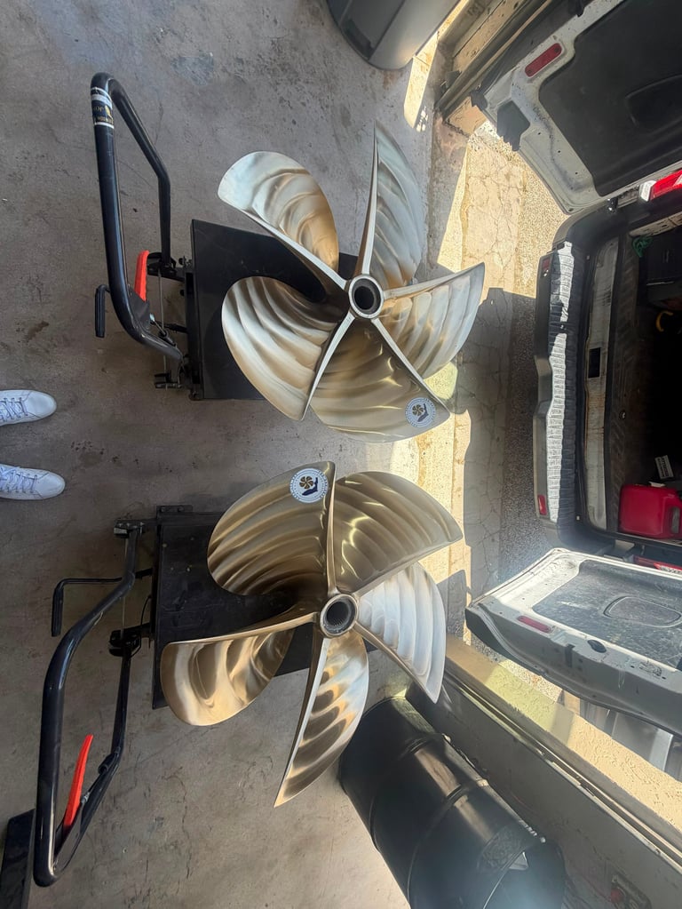 Two boat propellers mounted on garage floor next to open trunk, viewed from above